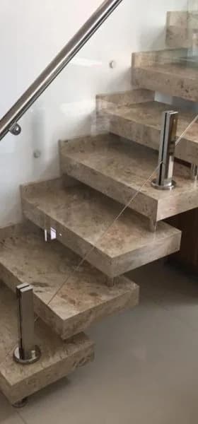 Escada com degraus em granito bege e guarda-corpo de vidro